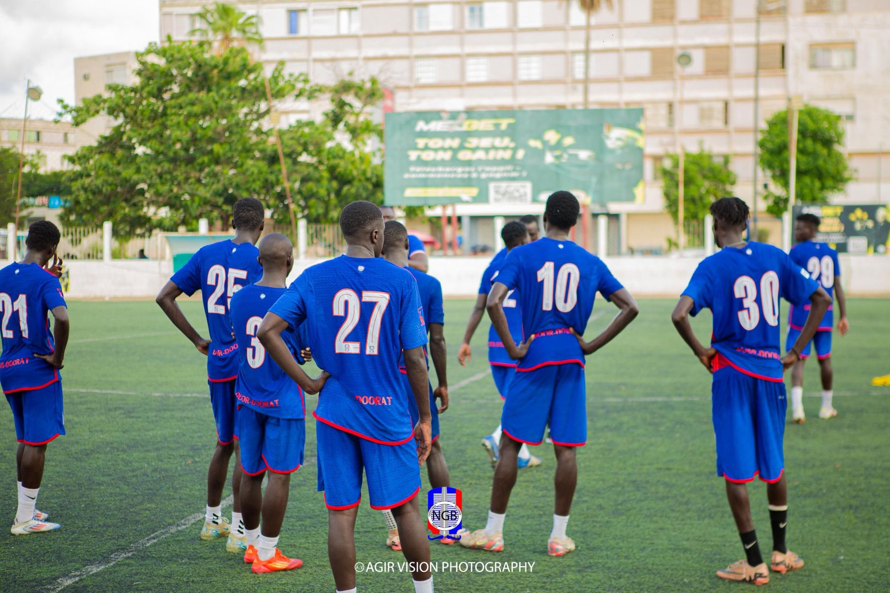 Les joueurs de NGB de dos, numéros sur le maillot bleu, sur la pelouse de Keur MIG